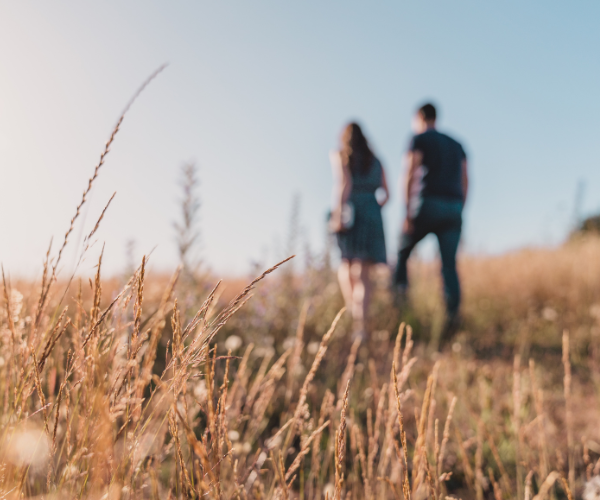 couple walking on tall grass fields